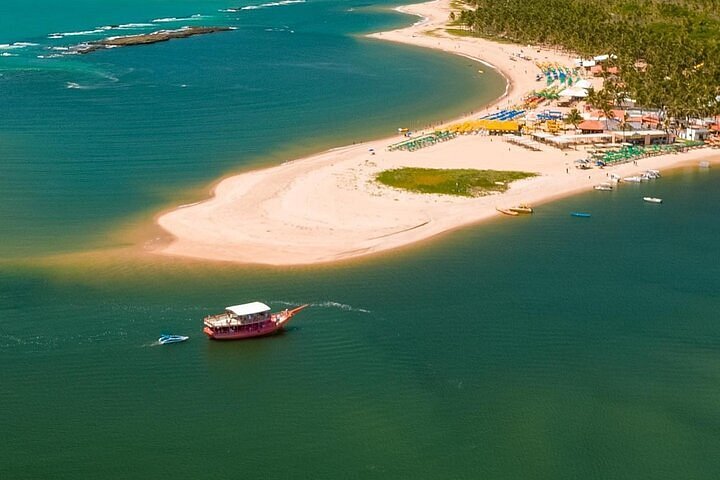 O Que Fazer na Praia do Gunga: Falésias, Lagoa do Roteiro e Aventuras Imperdíveis Se você está planejando sua viagem e se perguntando o que fazer na Praia do Gunga, prepare-se para descobrir um verdadeiro parque natural ao ar livre. Localizada no litoral sul de Alagoas, a praia é um mosaico de falésias multicoloridas, coqueirais infinitos, lagoas cristalinas e mirantes cinematográficos. O Gunga não é apenas um destino para relaxar à beira-mar — é um convite à aventura, à contemplação e às experiências inesquecíveis. Famílias encontram piscinas naturais perfeitas para crianças, casais se deixam levar por pores do sol românticos à beira da lagoa, e aventureiros aceleram em passeios de buggy pelas falésias que parecem cenário de filme. Para os que preferem um ritmo mais tranquilo, a pedida é navegar pela Lagoa do Roteiro, mergulhar em águas serenas e cristalinas ou simplesmente flutuar num banco de areia em meio ao azul esverdeado. Já quem busca os melhores registros fotográficos não pode deixar de subir aos mirantes do Gunga, de onde se descortinam panoramas que misturam mar, coqueiros e falésias em uma tela natural perfeita. Ao longo deste guia, você vai encontrar informações práticas de cada atividade — valores, tempo médio, perfis indicados, melhores horários e dicas de maré. O objetivo é simples: te ajudar a visualizar um dia perfeito no Gunga e voltar para casa com lembranças que ficam para sempre. 🌴✨ Falésias do Gunga: Paisagens esculturais e Passeios Inesquecíveis Entre todas as experiências da Praia do Gunga, poucas são tão marcantes quanto o encontro com suas falésias multicoloridas. São paredões imensos de areia compactada, esculpidos pela ação do tempo, que revelam camadas em tons de vermelho, laranja, bege e até roxo. Vistos de perto, parecem esculturas gigantes — e quando o sol bate de lado, ao amanhecer ou no fim da tarde, a paleta de cores se intensifica e cria uma paisagem de cinema. Chegar às falésias é como atravessar um portal: em poucos minutos você sai do mar turquesa e se vê diante de um cenário quase desértico, onde o silêncio é cortado apenas pelo vento e pelo ronco dos buggies passando pelas trilhas. É uma experiência que mistura aventura com contemplação, ideal para quem gosta de sentir o contraste entre natureza bruta e beleza delicada. Passeio de Buggy: Aventura em Alta Velocidade com Paradas Incríveis A forma mais popular — e emocionante — de explorar as falésias do Gunga é o passeio de buggy. Os veículos saem da própria praia, guiados por motoristas credenciados, e percorrem trajetos que duram de 40 a 60 minutos. Roteiro: começa na areia da praia, sobe pelas trilhas de areia batida, atravessa o coqueiral e faz paradas estratégicas em miradouros naturais. Em cada ponto, há tempo para fotos e para contemplar as falésias de ângulos diferentes. Valor médio em 2025: entre R$60 e R$80 por pessoa, dependendo do trajeto escolhido. Perfil indicado: famílias (crianças a partir de 5 anos, acompanhadas), casais e aventureiros. Sensação: vento no rosto, areia nos pés e aquela leve adrenalina de estar em movimento entre paisagens cinematográficas. É uma atividade que agrada a todos os estilos: os mais aventureiros adoram a velocidade, enquanto os contemplativos aproveitam as paradas para registrar cada detalhe do cenário. Dica Extra: Quando as Falésias Estão Mais Coloridas? A intensidade das cores varia de acordo com a posição do sol. Manhã (8h–10h): luz suave, tons avermelhados mais vivos. Fim da tarde (15h30–17h): iluminação dourada, falésias ganham profundidade e contraste. Meio-dia: luz mais dura, bom para realçar o contraste com o céu azul. 👉 Para os apaixonados por fotografia, vale instalar aplicativos como PhotoPills ou Sun Seeker, que mostram os horários ideais de luz no ponto exato das falésias. Lagoa do Roteiro: Águas Claras, Relax e Passeio de Barco Se o mar da Praia do Gunga já é fascinante por si só, imagine quando ele se encontra com a serenidade da Lagoa do Roteiro. É ali, no lado esquerdo da praia, que o doce e o salgado se encontram, formando um espetáculo de contrastes que rende momentos de pura contemplação. A lagoa é perfeita para quem busca relaxamento: a água é calma, morna e pouco profunda em vários trechos, ideal para famílias com crianças pequenas ou para casais que querem apenas flutuar e curtir o silêncio. Durante a maré baixa, bancos de areia emergem no meio da água, criando verdadeiras “ilhas temporárias” onde é possível caminhar e se sentir no meio de um cenário de cinema. Além do banho tranquilo, a Lagoa do Roteiro é ponto de partida para passeios que revelam o Gunga de ângulos inéditos. Passeios de Catamarã e Lanchinha: Vale a Pena? Uma das formas mais populares de explorar a lagoa é embarcar em catamarãs ou lanchinhas que fazem a travessia até o Gunga ou roteiros panorâmicos pela região. Catamarã coletivo: acomoda dezenas de pessoas, com música ambiente, serviço de bar e paradas para banho em bancos de areia. Duração: cerca de 1h30. Valor em 2025: em média R$70 a R$90 por pessoa. Lanchinha rápida: embarcação menor e mais ágil, ideal para quem prefere grupos reduzidos ou um passeio mais íntimo. Duração: cerca de 40 minutos. Valor em 2025: a partir de R$50 por pessoa. 👉 Casais costumam preferir as lanchinhas, principalmente no fim da tarde, quando o pôr do sol tinge a água de tons dourados. Já famílias e grupos de amigos optam pelo catamarã, que transforma o trajeto em uma mini-festa sobre as águas. Snorkeling: Onde Estão as Piscinas Naturais Mais Claras da Região? A Lagoa do Roteiro também guarda boas surpresas para quem gosta de observar a vida marinha. Em dias de maré baixa, formam-se piscinas naturais cristalinas próximas aos bancos de areia. É possível praticar snorkeling com máscara e snorkel simples — equipamentos que podem ser alugados em barracas locais por R$20 a R$30. Melhor horário: manhã, quando a luz do sol atravessa a água e aumenta a visibilidade. Dica: leve sapatilhas aquáticas para caminhar sobre áreas com conchinhas e pedras. Flutuar sobre essas piscinas é uma das experiências mais tranquilas do Gunga, perfeita para desligar da correria e se reconectar com a natureza. Mirantes do Gunga: Os Melhores Pontos para Fotos Incríveis Se a Praia do Gunga já impressiona de perto, do alto ela se transforma em uma pintura viva. Os mirantes oferecem vistas panorâmicas que combinam o azul intenso do mar, o verde interminável do coqueiral e os tons terrosos das falésias. É dali que surgem as fotos mais famosas do destino — aquelas que imediatamente viram cartão-postal. Além da beleza, os mirantes são facilmente acessíveis: alguns ficam bem próximos à entrada da praia, enquanto outros exigem passeios de buggy ou caminhada leve entre os coqueiros. Mirante do Gunga (Principal) Localização: acesso principal da praia, ao lado do estacionamento. Estrutura: deck de madeira elevado, com espaço para fotos e barraquinhas de artesanato. Custo em 2025: entrada entre R$15 e R$25 por pessoa. Melhor horário: manhã para cores mais vivas; fim da tarde para luz dourada. 👉 É o ponto mais procurado, perfeito para ver o coqueiral se estendendo até onde a vista alcança. Mirante da Petúnia Localização: dentro do percurso dos passeios de buggy. Diferencial: vista privilegiada para as falésias multicoloridas. Custo: incluso no valor do passeio de buggy. Perfil: indicado para quem quer registros mais exclusivos, longe do movimento do mirante principal. Mirante do Bené Localização: área alta no final do trajeto de buggy. Diferencial: vista ampla que combina lagoa e mar, com menos fluxo de visitantes. Melhor horário: fim da tarde, com céu alaranjado refletindo nas águas. Mirante do Falcão Localização: também acessível via buggy ou quadriciclo. Diferencial: panorâmica quase aérea da região, ideal para vídeos em drone. Perfil: recomendado para quem busca ângulos criativos e novas perspectivas. 📸 Dica Local: para capturar o coqueiral em toda sua grandiosidade, use a lente grande-angular do celular ou câmera. E se possível, planeje sua visita em dias de céu limpo — o contraste entre verde e azul fica ainda mais intenso. Trilhas, Natureza e Ecoturismo no Gunga Para além do mar azul e das falésias vibrantes, a Praia do Gunga também é um convite à conexão com a natureza em sua forma mais pura. O coqueiral que cerca toda a região não é apenas um cenário fotogênico: ele abriga pequenas trilhas, áreas de sombra refrescante e uma biodiversidade que pode surpreender os mais atentos. Caminhar pelo Gunga fora da faixa de areia é descobrir um outro ritmo. Entre os coqueiros, pequenas trilhas levam a clareiras silenciosas, pontos de observação da lagoa e até a caminhos que conectam aos mirantes mais afastados. Não é necessário preparo físico intenso — basta disposição para andar em terreno arenoso e sapatos confortáveis (ou sandálias com boa aderência). Turismo Consciente Com o aumento do fluxo de visitantes, cresce também a responsabilidade de preservar. Em 2025, iniciativas locais incentivam o turismo consciente, com placas educativas e até guias comunitários oferecendo caminhadas interpretativas. Nesses passeios, é possível aprender sobre a flora da região, ouvir histórias locais e compreender a importância da preservação das falésias. 👉 Recomendações práticas: Leve sempre sua garrafinha de água reutilizável. Evite descartar lixo ao longo das trilhas (existem pontos de coleta nas barracas principais). Use protetor solar biodegradável, especialmente se for praticar snorkeling ou caiaque. Experiência Sensorial As trilhas do Gunga são um convite a perceber detalhes que passam despercebidos na correria. O som do vento balançando milhares de coqueiros, o cheiro doce da vegetação aquecida pelo sol e a sensação da areia fina nos pés lembram que o Gunga é, antes de tudo, um lugar de contemplação. É a atividade ideal para viajantes que querem desacelerar, respirar fundo e absorver o ambiente além das fotos — um lado mais íntimo e silencioso do paraíso alagoano. 🌴✨ Passeios Alternativos: Quadriciclo, Caiaque e SUP Se os passeios de buggy e barco já são clássicos da Praia do Gunga, há quem prefira explorar o destino de forma menos óbvia. É aí que entram os passeios alternativos: quadriciclo pelas trilhas, caiaque na lagoa e stand up paddle (SUP) sobre as águas tranquilas. Atividades que misturam aventura, contato com a natureza e, claro, momentos divertidos para quem gosta de experimentar algo novo. Quadriciclo: Aventura Sobre Quatro Rodas Como funciona: saídas guiadas, partindo do estacionamento principal ou das barracas. O percurso passa por trechos de areia, coqueirais e até pequenas subidas em direção às falésias. Duração: cerca de 40 minutos à 1h. Valor médio em 2025: R$120 a R$150 por quadriciclo (2 pessoas podem dividir). Perfil indicado: jovens, casais e aventureiros que querem sentir mais controle do trajeto. Dica: leve óculos escuros e protetor solar, pois a areia levantada pelo veículo pode incomodar. 👉 Uma versão mais interativa do buggy, já que você mesmo conduz o veículo (sempre com monitoramento de guias). Caiaque: Flutuar em Ritmo Leve Onde acontece: na Lagoa do Roteiro, especialmente em dias de maré baixa, quando a água fica mais calma e cristalina. Duração: passeios livres, geralmente 30 a 60 minutos. Valor médio em 2025: R$40 a R$60 por caiaque (para 1 ou 2 pessoas). Perfil indicado: famílias, casais e viajantes que querem contato próximo com a natureza. Dica: vá no início da manhã ou fim da tarde, quando o sol não está tão forte e o reflexo da lagoa fica ainda mais bonito. SUP (Stand Up Paddle): Equilíbrio e Contemplação Onde acontece: também na Lagoa do Roteiro, em áreas rasas e seguras. Duração: em média 40 minutos. Valor médio em 2025: R$50 a R$70 por prancha. Perfil indicado: ideal para quem busca experiência calma e fotogênica, com possibilidade de remar até bancos de areia próximos. Dica: use colete salva-vidas e vá de roupa leve — cair na água faz parte da diversão. Essas atividades não costumam estar nos roteiros mais vendidos, mas são perfeitas para quem gosta de experiências autênticas. No ritmo do quadriciclo, no balanço do caiaque ou no equilíbrio do SUP, o Gunga revela nuances que não se vê de cima de um buggy ou de dentro de um catamarã. Planeje com Inteligência: Horários, Maré e Aplicativos Úteis Visitar a Praia do Gunga é simples, mas viver a experiência perfeita exige atenção a alguns detalhes práticos. O clima, a posição do sol e, principalmente, a maré influenciam diretamente nas atividades, na cor da água e até na lotação da praia. Planejar com cuidado é o segredo para transformar um dia comum em uma memória inesquecível. A Maré: O Fator-Chave No Gunga (assim como em outras praias do litoral sul de Alagoas), a maré baixa é responsável por revelar piscinas naturais cristalinas e garantir o mar mais calmo e translúcido. Já a maré alta traz ondas maiores e pode limitar algumas atividades, como snorkeling ou SUP. 👉 Antes de viajar, consulte a tábua de marés e monte seu roteiro priorizando os dias com maré mínima abaixo de 0,5 m. Melhor Horário do Dia Manhã (8h–11h): clima mais fresco, maré geralmente baixa, ótima luz para fotografias. Meio do dia (11h–14h): sol intenso, bom para quem gosta de mar agitado, mas exige protetor solar reforçado. Fim da tarde (15h–17h30): luz dourada, menos calor e pores do sol espetaculares na Lagoa do Roteiro. 👉 Para os passeios de buggy pelas falésias, manhãs e fins de tarde são os melhores momentos: menos calor e cores mais vivas nas fotos. Aplicativos Úteis para Sua Viagem Climatempo → previsões de sol, vento e chuva para planejar o dia. Tábua de Marés Brasil → consulta rápida sobre os horários exatos de maré alta e baixa. Windy App → ideal para quem vai praticar esportes aquáticos, mostrando intensidade e direção do vento. PhotoPills / Sun Seeker → para fotógrafos e criadores, mostram posição e intensidade da luz do sol ao longo do dia. 📱 Dica Local: baixe esses aplicativos antes da viagem e ative o modo offline para não depender de sinal de celular durante os passeios. Planejar é mais do que organizar horários: é abrir espaço para que o Gunga revele seu lado mais bonito no momento certo. FAQ – Perguntas Frequentes 1 - Quais os passeios mais recomendados para quem vai com crianças? Passeios de barco pela Lagoa do Roteiro e banho nas piscinas naturais em dias de maré baixa. As águas são calmas e rasas, perfeitas para os pequenos. 2 - O passeio de buggy é seguro para idosos? Sim, desde que feito com motoristas credenciados. O trajeto tem algumas subidas e descidas, mas é conduzido em velocidade controlada. 3 - Quanto tempo dura o passeio de barco? Os catamarãs duram em média 1h30, enquanto as lanchinhas rápidas ficam entre 40 e 60 minutos. 4 - Precisa reservar os passeios com antecedência? Na alta temporada (dezembro a março), sim. Buggy e barco esgotam rápido. Fora desse período, é possível contratar diretamente na praia. 5 - É possível fazer todos os passeios em um único dia? É possível, mas pode ficar corrido. O ideal é escolher entre buggy + lagoa ou buggy + mirantes, deixando atividades extras (SUP, trilhas) para outro dia. 6 - Qual o horário ideal para ver as falésias coloridas? As manhãs (8h–10h) e fins de tarde (15h–17h) oferecem a luz mais bonita para fotografia. Viva o Melhor da Praia do Gunga em Cada Experiência A Praia do Gunga é mais do que um destino de praia: é um palco de aventuras, contemplação e descobertas. Das falésias esculpidas pela natureza à calmaria da Lagoa do Roteiro, passando por mirantes cinematográficos e passeios de buggy cheios de energia, cada visitante encontra um pedacinho do paraíso para chamar de seu. Seja você um viajante que busca emoção, descanso, boas fotos ou momentos em família, o Gunga tem um roteiro feito sob medida. Cabe a você montar a combinação perfeita de experiências — e esse guia é o ponto de partida para transformar seu planejamento em realidade. 🌴✨ 💬 E você, já visitou a Praia do Gunga? Compartilhe sua experiência nos comentários e inspire outros viajantes a viverem esse paraíso. 📩 Assine nossa newsletter! Quer mais histórias curiosas, dicas locais e guias completos sobre a Praia do Gunga? 📩 Assine nossa newsletter e receba conteúdos inéditos direto no seu e-mail. 